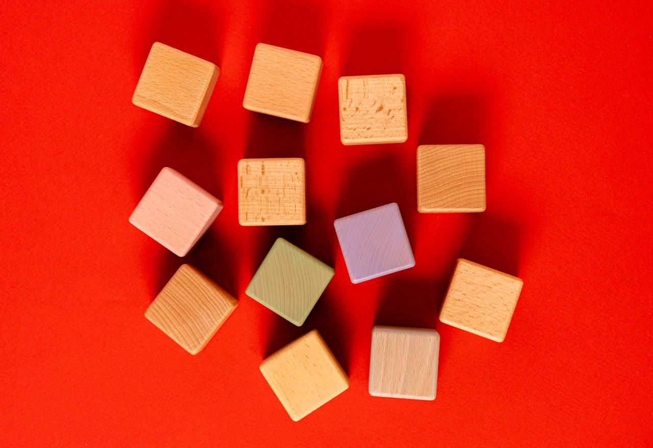 Arrangement of multicolored wooden blocks on a bright red surface.